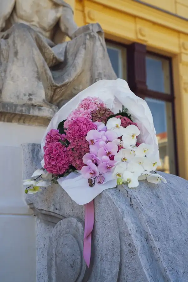 Buket u bijelom papiru na kamenoj ogradi